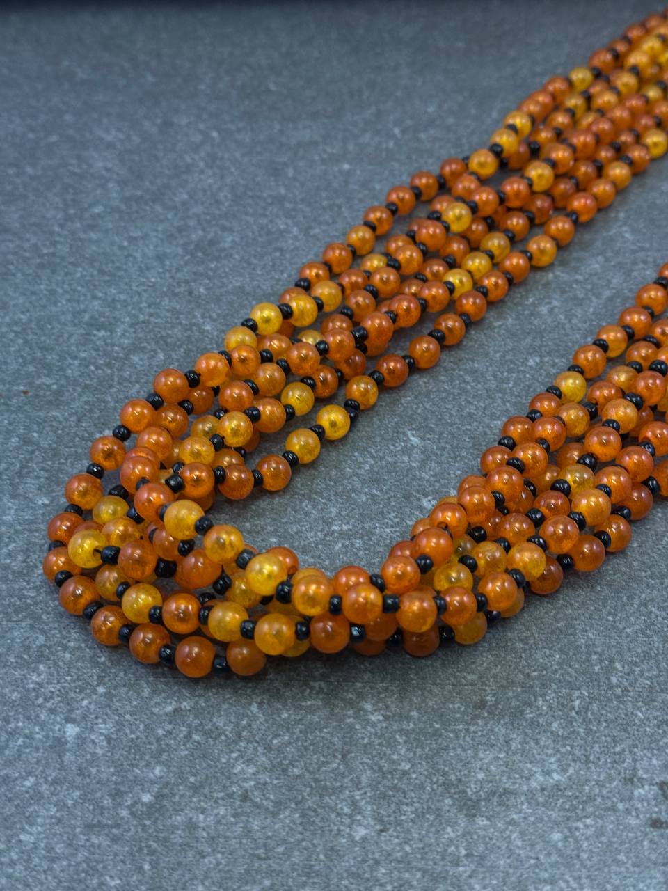 Halskette mit orangefarbenen, schwarzen Harzperlen und Hakenverschluss