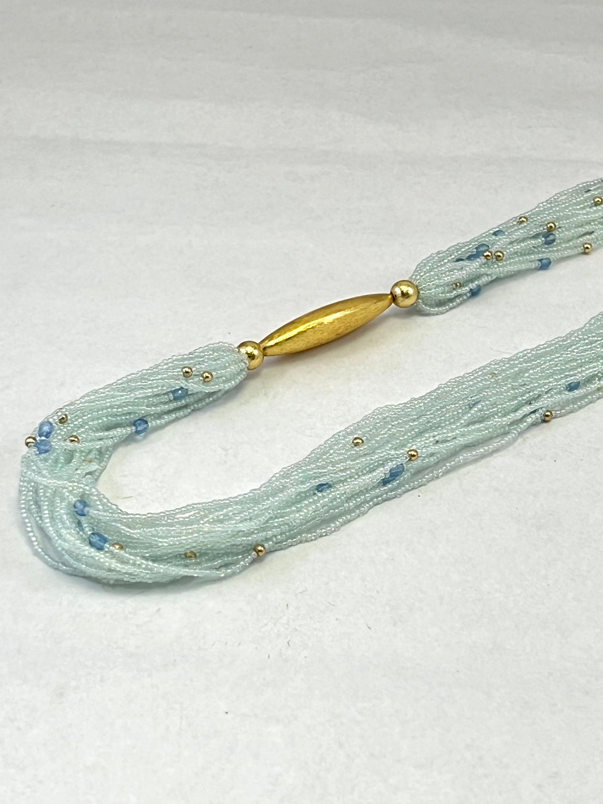 COLLIER MULTICOUCHE EN PERLES DE ROCAILLE JECKO DORÉES ET PERLES CRIS AVEC FIL